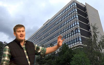 An enthusiastic member of the international support team in front of the main building.